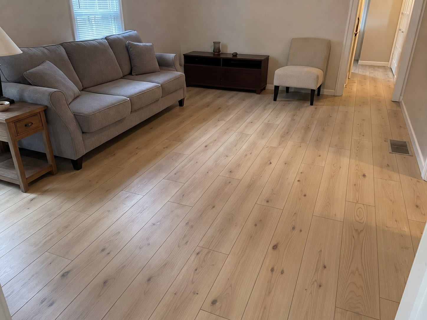 Living room with Shaw Oyster Oak light warm luxury vinyl plank flooring continuing through the open hall.
