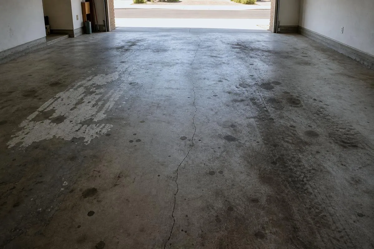 Cracked and stained bare concrete garage floor before coating